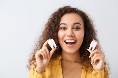 girl holding two teeth and smiling