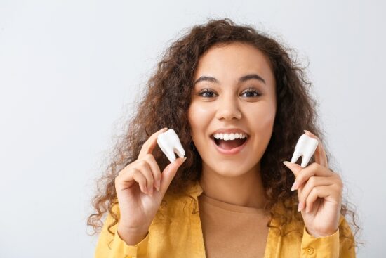 girl holding two teeth and smiling