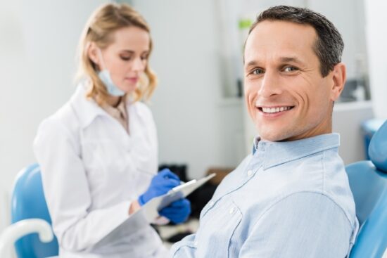 man seating in the treatment chair next to dentist
