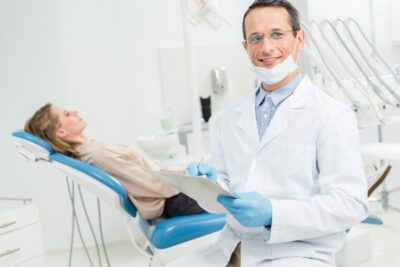 male dentist with patient in the background