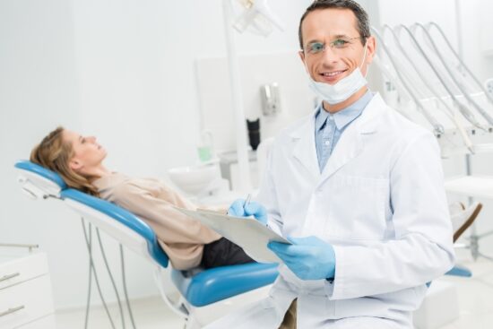 male dentist with patient in the background