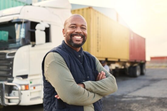 man in a vest standing outside a truck and smiling