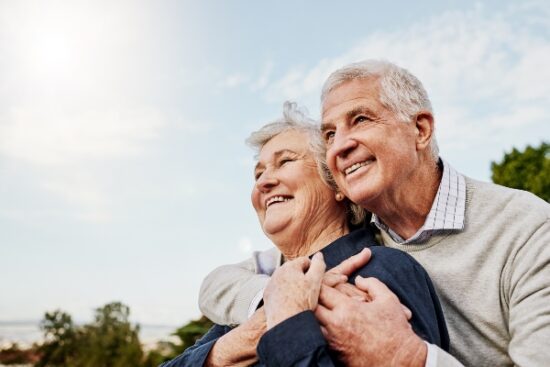 older couple outside hugging and smiling