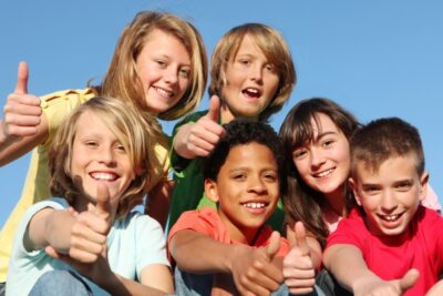group of children smiling and giving a thumsb up