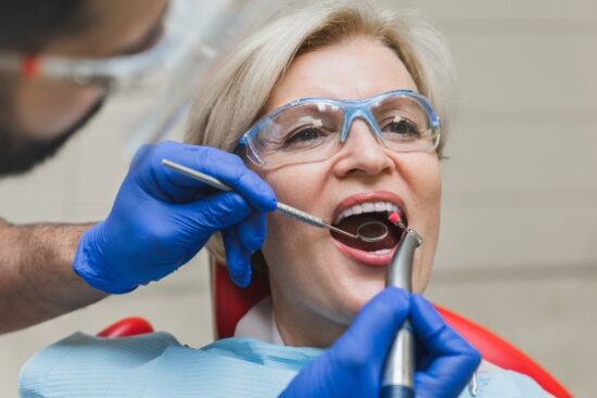 older woman wearing goggles and undergoing emergency dental care