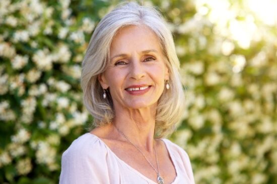 older woman standing outside and smiling