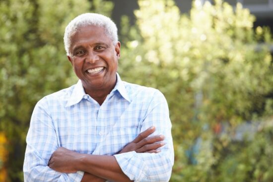 older man with white hair smiling while outside