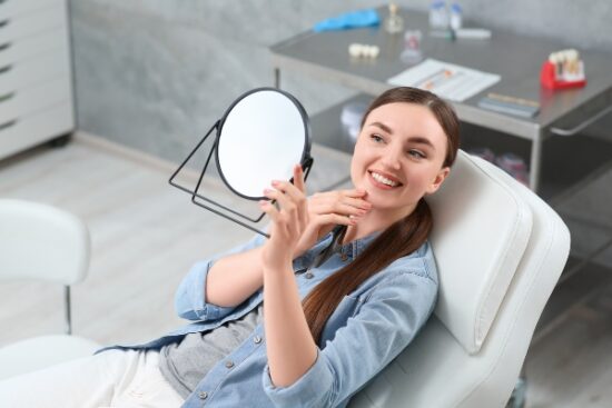 young woman looking at her smile in the mirror