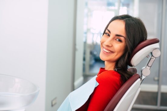 woman in red blouse seated in a treatment chair