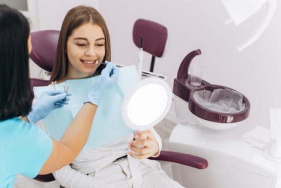 dentist holding a shade guide up to a patient's smile
