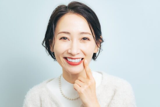woman with red lipstick pointing to her smile