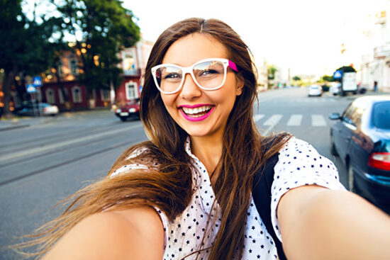 young woman with glasses smiling outside
