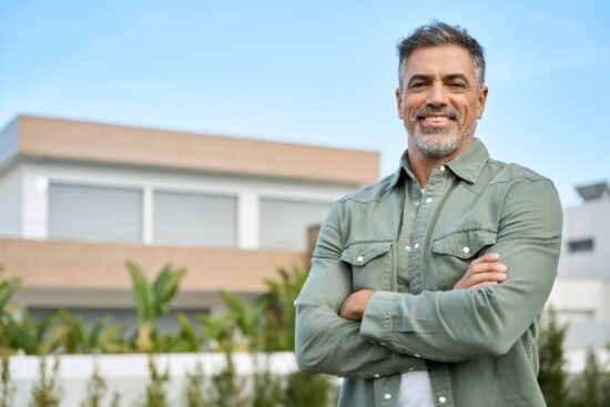 middle-aged man smiling and standing in front of a building
