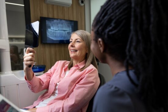 older woman happy with her smile and looking in the mirror