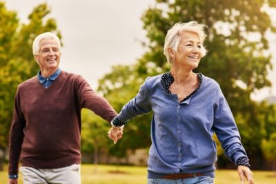 older couple smiling and holding hands outside